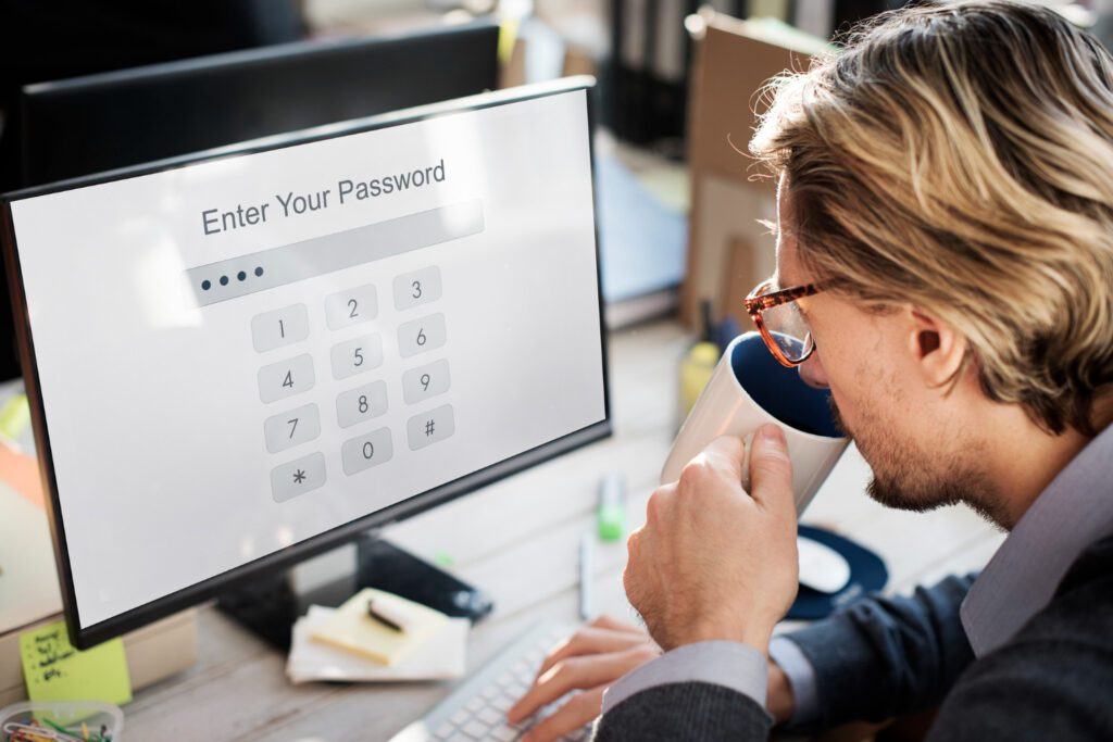 A person enters a password on his desktop using a numeric keypad while sipping coffee.